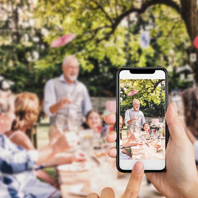 Bilder in einem gemeinsamen Online-Fotoalbum speichern Frau macht Foto von Feier und speichert diese via Handy direkt im digitalen Fotoalbum auf sendmoments.de